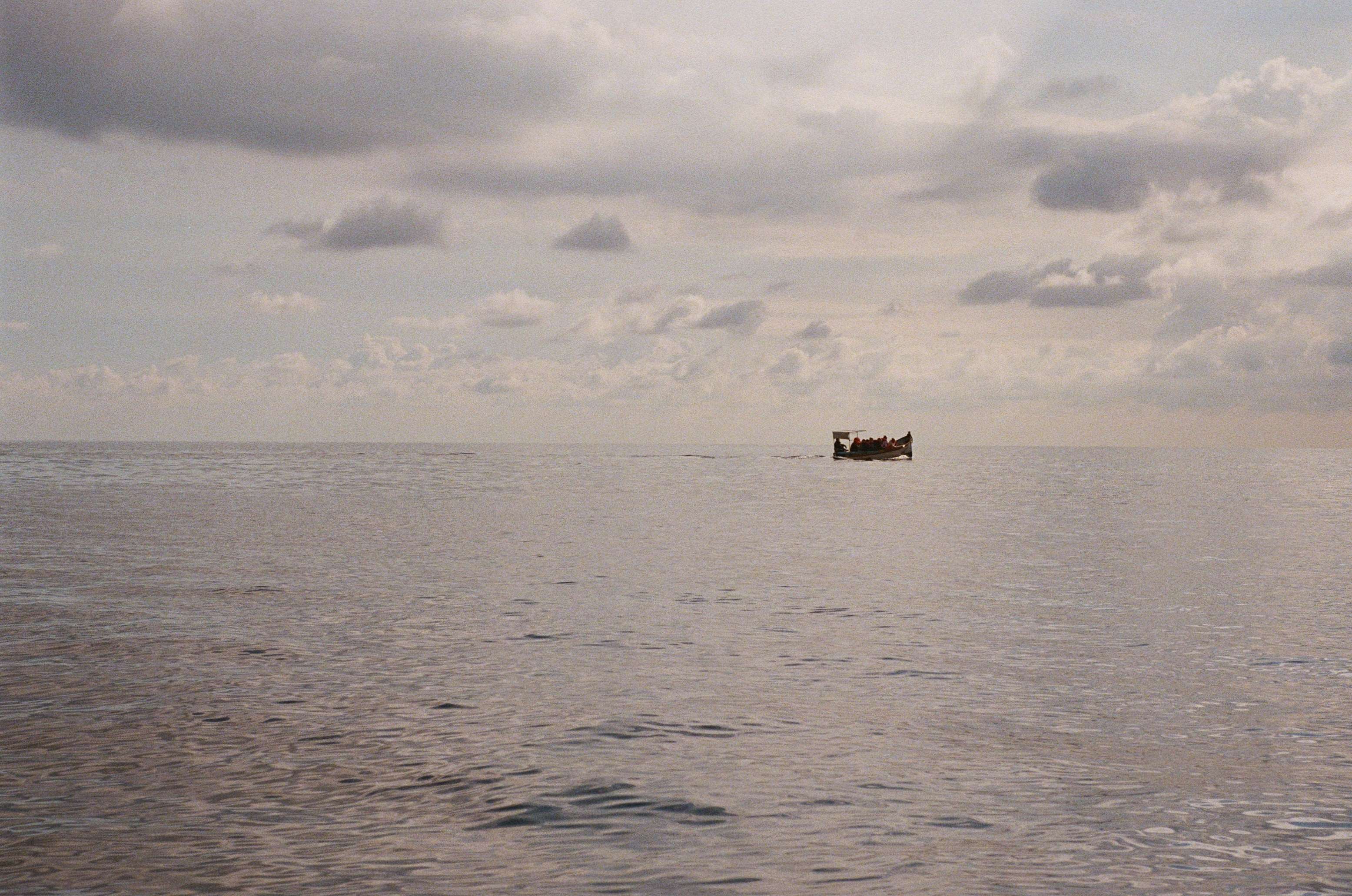 A picture of the sea, with a small boat full of people in the distance.